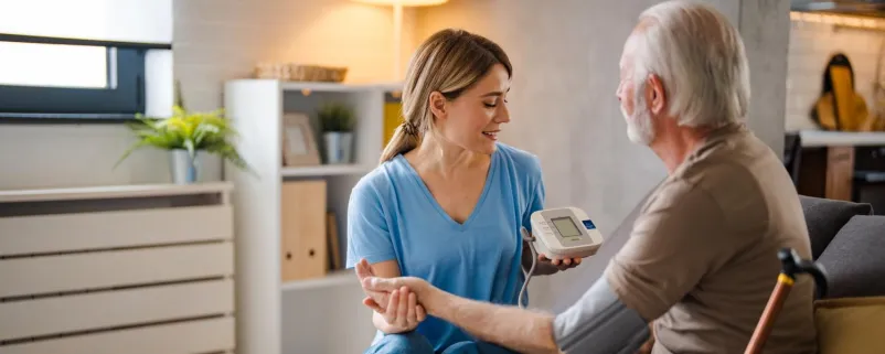 Krankenschwester misst bei einem Mann den Blutdruck