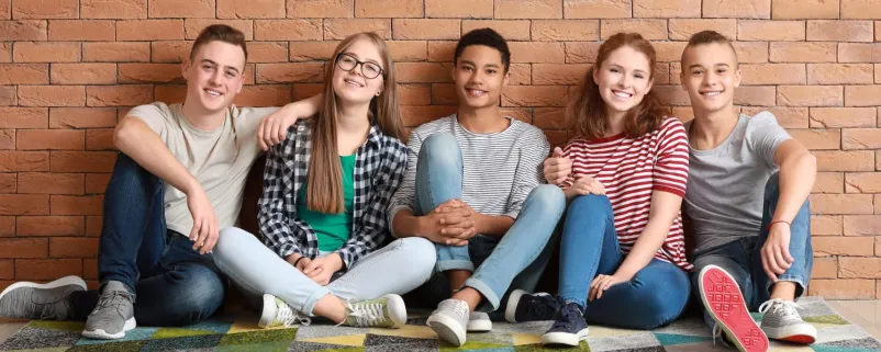 Gruppe von Jugendlichen sitzt vor einer Mauer