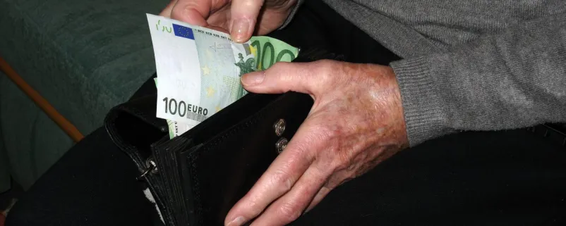 Mann zieht Geldschein aus Geldbörse