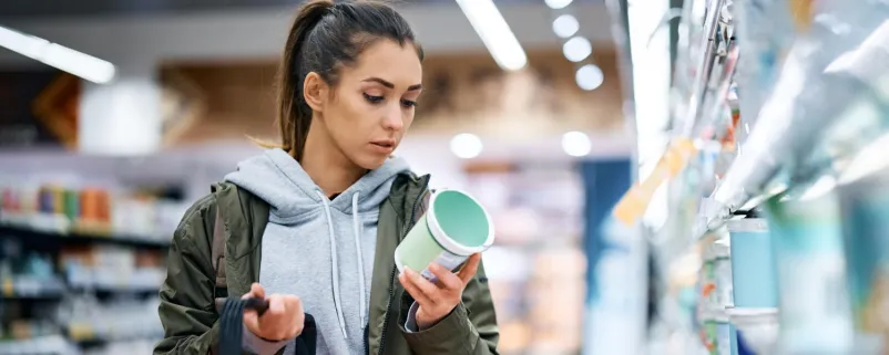 Frau vergleicht im Supermarkt Preise