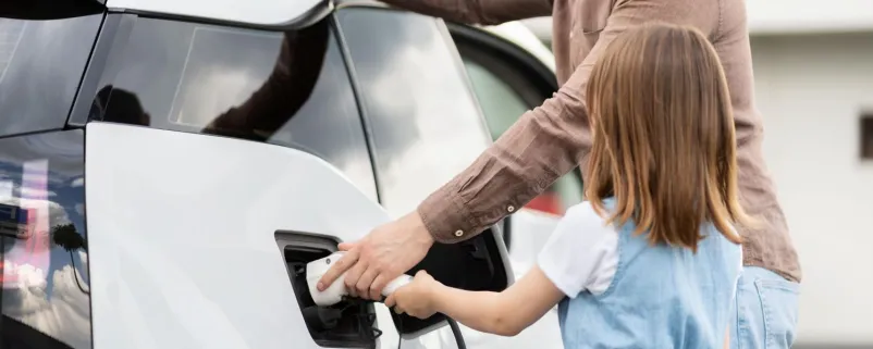 Mann und Kind tanken E-Auto