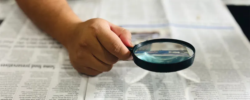 Zeitung mit Lupe lesen