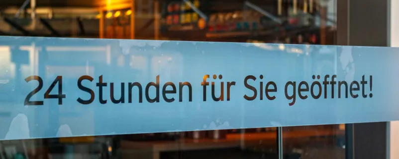 Schaufenster von Ladengeschäft mit Schild „24 Stunden für Sie geöffnet“
