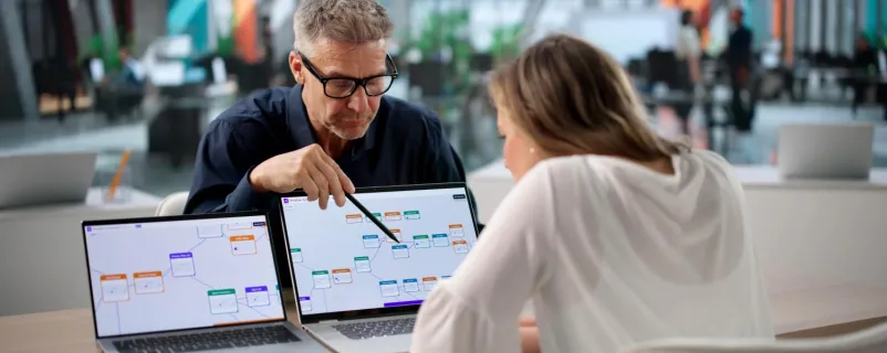 Mann und Frau arbeiten gemeinsam an 2 Laptops