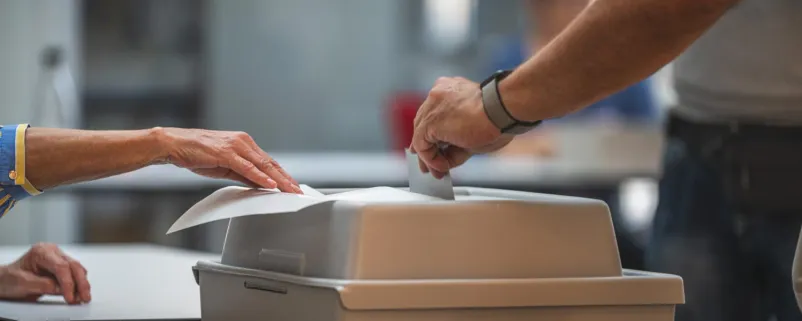 Wähler wirft seinen Stimmzettel in die Wahlurne