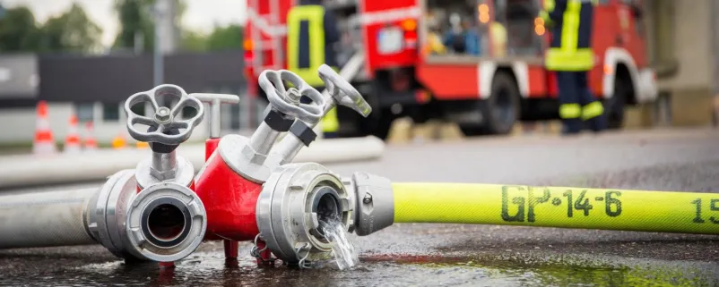 Feuerwehrschlauch und Auto im Hintergrund