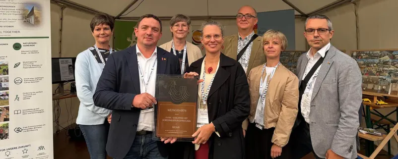 Landeshauptmann-Stellvertreterin Anja Haider-Wallner (vorne Bildmitte) und Bürgermeister Thomas Stoiber (2.v.l.) mit dem Europäischen Dorferneuerungspreis für den Dorftreff in Weingraben.