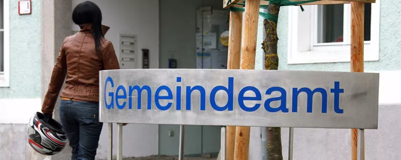 Frau und Gemeindeamt-Schild