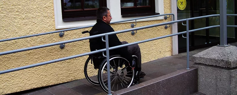 Mann mit Rollstuhl auf Rampe