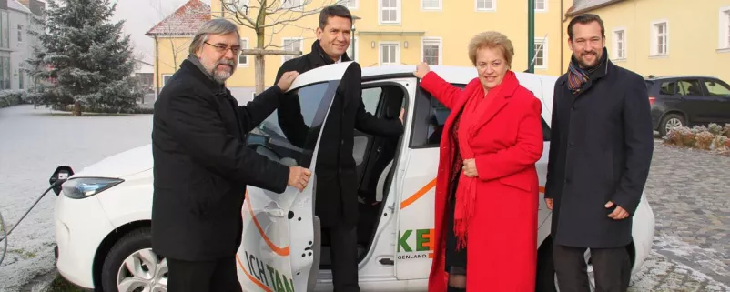 Vier Personen vor E-Auto