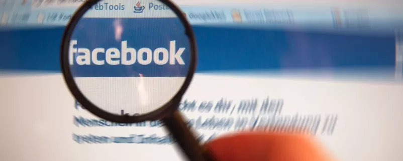 Facebook-Logo wird mit Lupe betrachtet