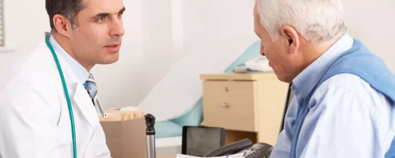 Arzt spricht mit älterem Patienten