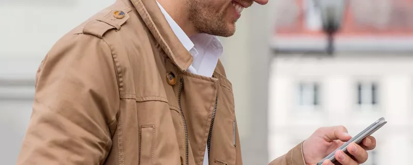 Mann mit Lederjacke schaut auf Smartphone