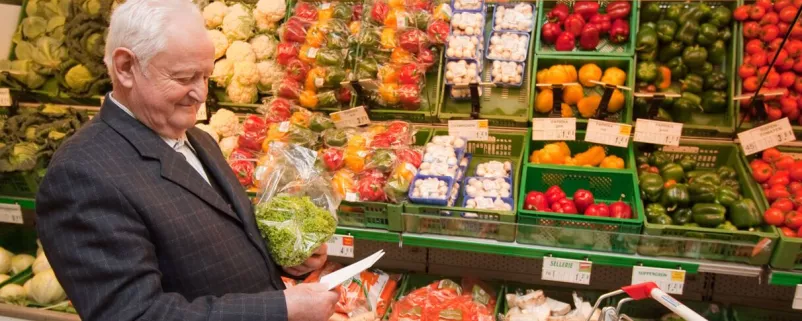 Alter Mann steht vor regionalem Gemüseregal