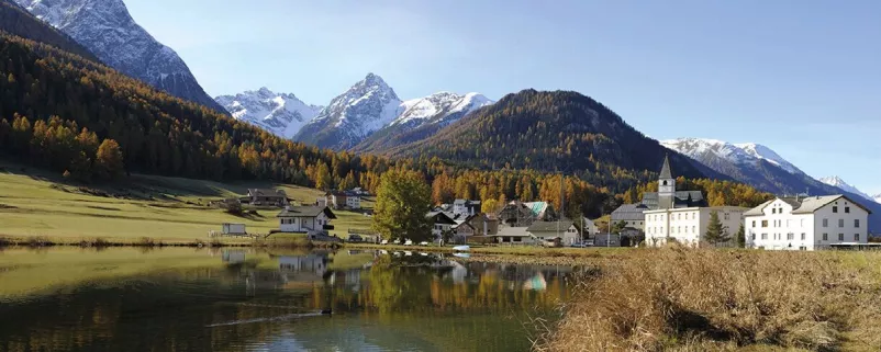 See, Dorf und verschneite Bergspitzen