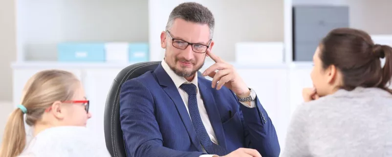 Mann in Anzug hört zwei Mitarbeiterinnen zu