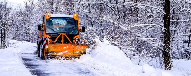 Räumfahrzeug räumt Waldstraße von Schnee