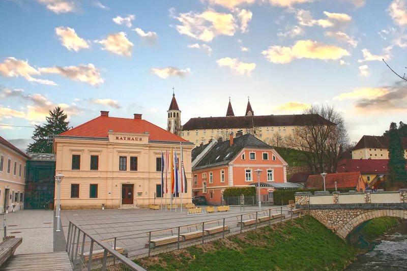 Das Ortszentrum von St.Paul mit Rathaus, dem davor fließenden Granitzbach, und dem Benedekitinerstift im Hintergrund.