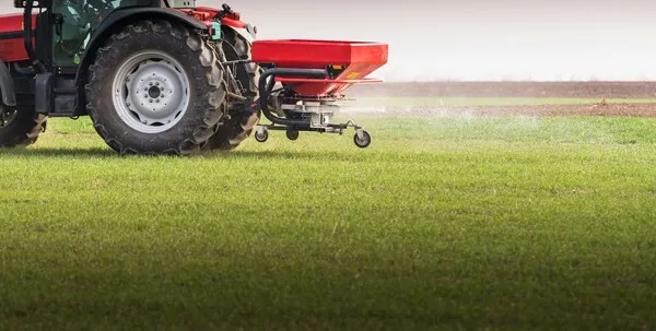 Traktor verteilt Klärschlamm auf Feld