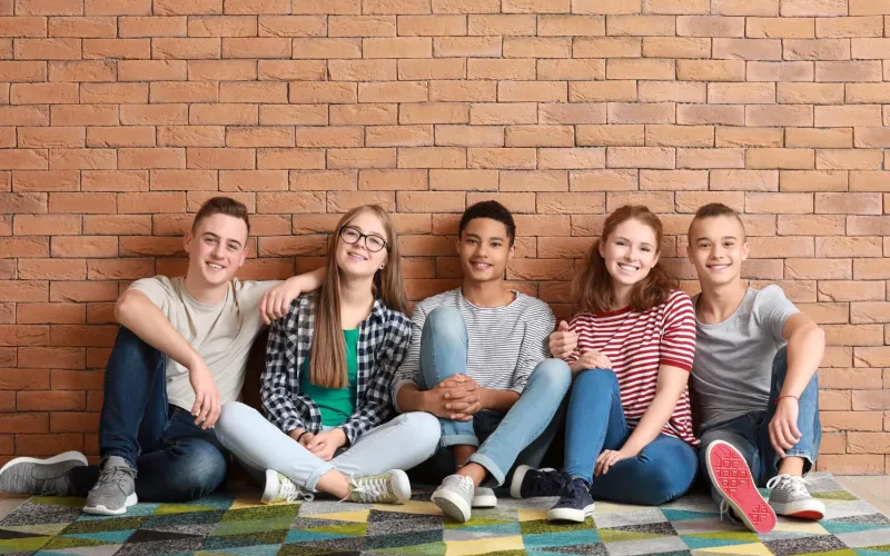 Gruppe von Jugendlichen sitzt vor einer Mauer