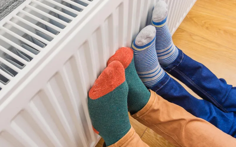 Menschen halten ihre Füße an einen Heizkörper