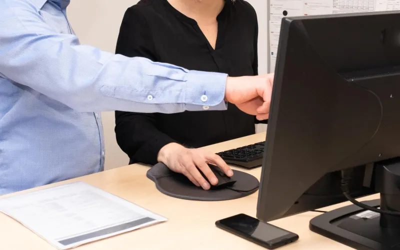 a man and a woman working together on a pc, man pointing at screen