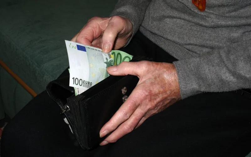 Mann zieht Geldschein aus Geldbörse