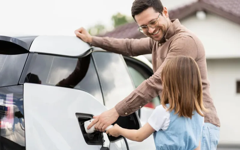 Mann und Kind tanken E-Auto