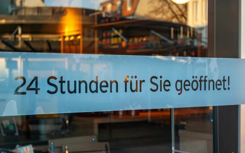 Schaufenster von Ladengeschäft mit Schild „24 Stunden für Sie geöffnet“
