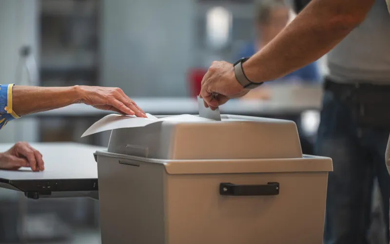 Wähler wirft seinen Stimmzettel in die Wahlurne
