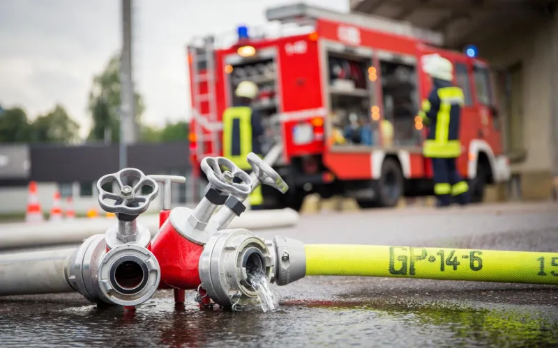 Feuerwehrschlauch und Auto im Hintergrund