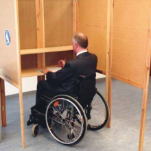 Rollstuhlfahrer in einer Wahlkabine
